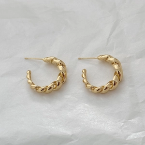 Detailed view of gold twisted rope C-shaped hoop earrings on white background