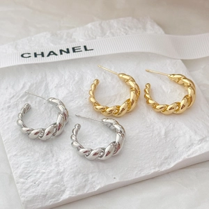 French retro twisted metal hoop earrings in gold and silver finish on white stone