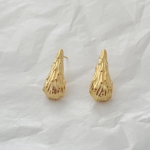Detailed view of 18K gold teardrop earrings featuring a unique molten lava texture design