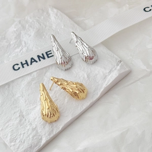 Detailed view of teardrop stud earrings with irregular lava texture in gold and silver