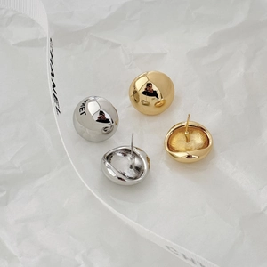 Macro view of minimalist spherical stud earrings in polished gold and silver finishes