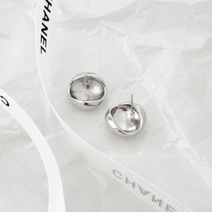 Minimalist silver irregular concave stud earrings with textured finish on white paper
