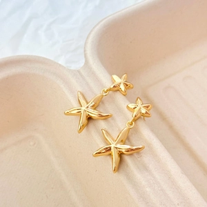 Détails macro des boucles d'oreilles étoile de mer dorées 18K avec design double étoile