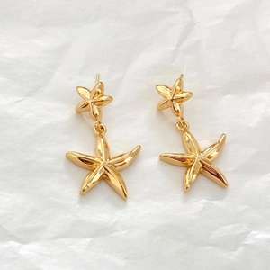 Boucles d'oreilles pendantes étoile de mer plaquées or 18 carats sur fond blanc épuré