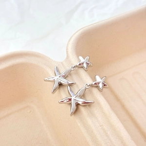 Boucles d'oreilles étoiles de mer plaquées or 18 carats sur fond crème minimaliste