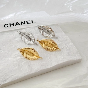 Detail view of gold and silver leaf-shaped earrings with intricate vein textures