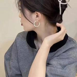Close-up of elegant gold hoop earrings and pearl hair claw clip on a female model