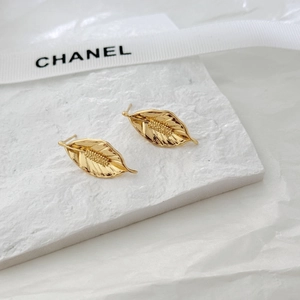 Macro detail of gold leaf stud earrings with realistic natural texture on stone display