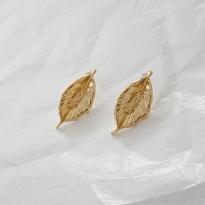Macro shot of gold leaf earrings showing intricate veins and delicate floral texture