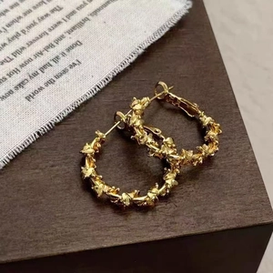 Retro golden hoop earrings with intricate relief texture shown on vintage fabric base