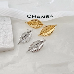Macro detail of leaf stud earrings with intricate textures in gold and silver finish