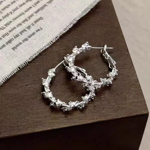 Retro silver vine floral earrings on a dark wood and fabric display background