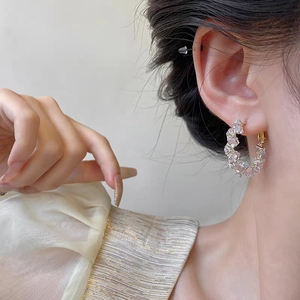 Gros plan d'élégantes créoles dorées serties de zircons portées par un mannequin