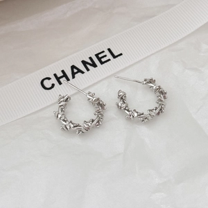 Macro shot of silver C-shape earrings with twisted texture on white ribbon background