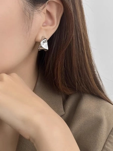 Close-up of a minimalist silver irregular twisted earring on a female model