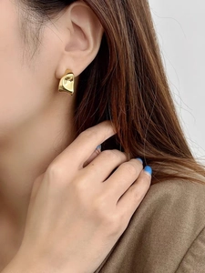 Close-up of a model wearing minimalist golden irregular geometric metal earrings