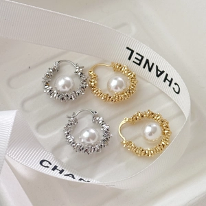 Elegant gold and silver hoop earrings with white pearls on a textured white tray