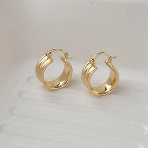 Détail de boucles d'oreilles créoles larges plaquées or 18K avec texture à trois bandes
