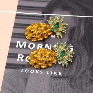 Detail of pineapple earrings with sparkling yellow and green crystals on gold base