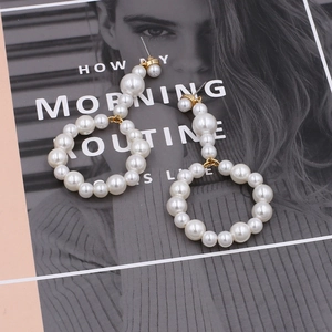 Detailed close-up of large white pearls and gold metal clasp on hoop earrings