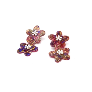 Close-up of double-layered floral acrylic earrings with colorful texture and pearl stamens