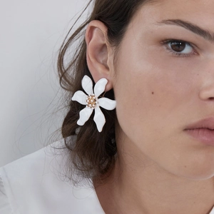 Elegante grote witte bloemenoorbellen met gouden kralen op een model in zijaanzicht