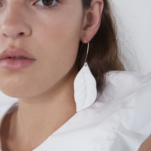 Chique witte blad oorbellen met gouden haken gedragen door een fashion model