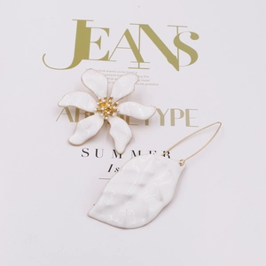 Detail van asymmetrische witte bloemknop en getextureerde bladhangers met gouden accenten