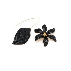 Detail van asymmetrische bloemen- en bladhangers met zwarte emaille en goudkleur