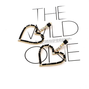 Detail of heart-shaped earrings with black stones and colorful crystals on gold base