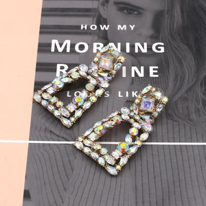 Close-up of geometric gold dangle earrings with colorful AB rhinestones on a fashion magazine