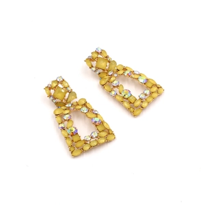 Macro shot of oversized yellow resin geometric earrings with aurora rhinestones