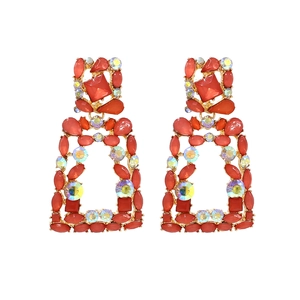 Macro shot of geometric drop earrings with coral red gems and iridescent crystals