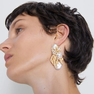 Luxury baroque pearl earrings with golden metal leaves on model for elegant style