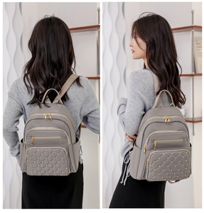 Detail view of grey quilted nylon backpack with gold studs and multi-layer zippers