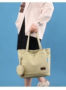 Detail of canvas tote bag with leather logo tag and hanging round coin purse accessory