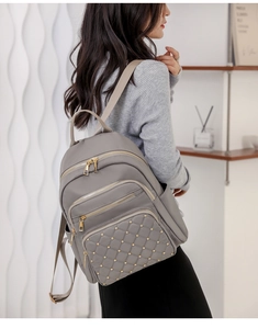 Close-up of grey oxford backpack featuring diamond quilted stitching and gold stud details