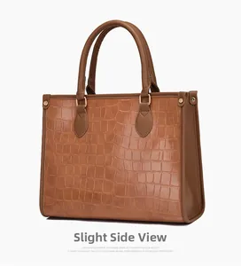 Slight side view of a large brown crocodile pattern tote bag with golden hardware