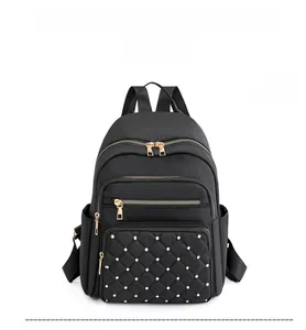 Detailed front view of black quilted oxford backpack with golden rivets and zippers