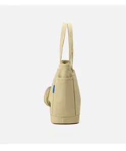 Detail view of beige canvas tote bag featuring side pockets and a round coin purse charm