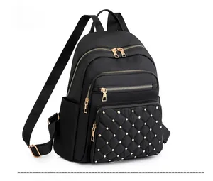 Profile view of black nylon backpack featuring quilted embroidery and gold rivets details