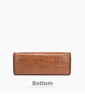 Detail view of brown crocodile pattern leather handbag bottom with reinforced stitching
