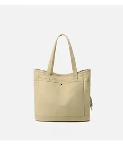 Detail of minimalist beige canvas tote bag with front snap pocket and side compartments