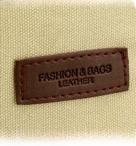 Close-up of leather logo patch on canvas bag showing stitching and fabric texture