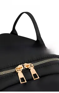Detail of durable webbing handle and dual golden zippers on black nylon backpack