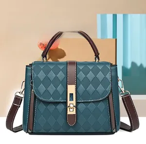 Détail du sac matelassé bleu canard avec bandoulière marron et fermoir doré rotatif