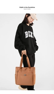 Détail d'un grand sac cabas en nylon marron avec poches latérales et fermeture éclair