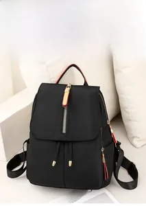 Detail view of water-resistant black oxford backpack with gold hardware and red zipper trim