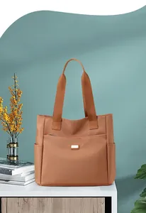 Détail d'un grand sac cabas en nylon marron avec poche zippée cachée sur table blanche