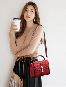 Détail d'un sac à main rouge en cuir matelassé avec boucle dorée et bandoulière